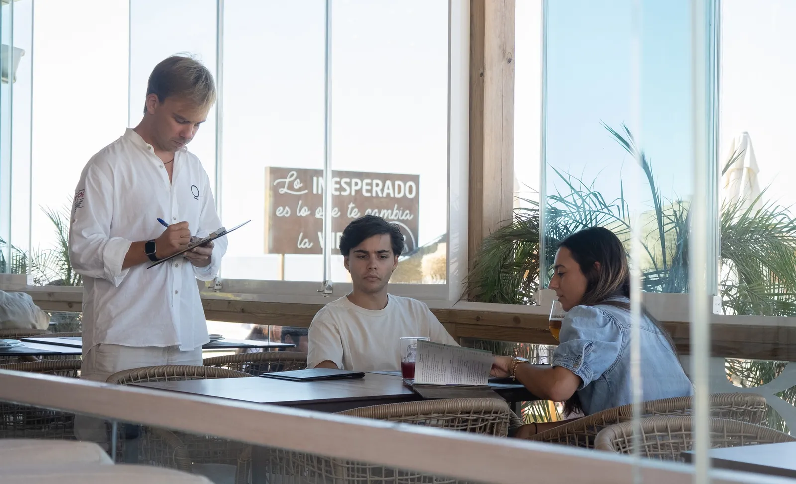 Camarero tomando nota en una mesa junto al ventanal